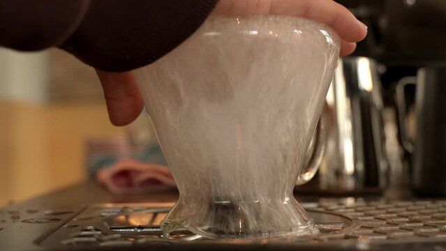 Close-up of a girl washing a dirty glass glass with a dish washer. Washing dirty cups in a coffee shop. Sterilization of dirty dishes. High quality 4k footage
