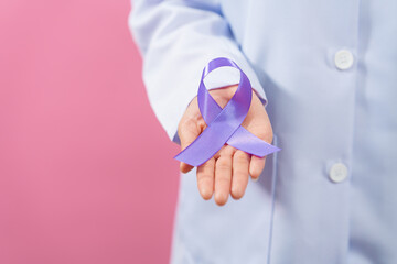 Prostate cancer awareness. Close up medical doctor holding ribbon over pink background isolated....