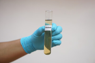 Close up hand wears blue glove holds test tube of biodiesel. Concept. Science reseach to develop...
