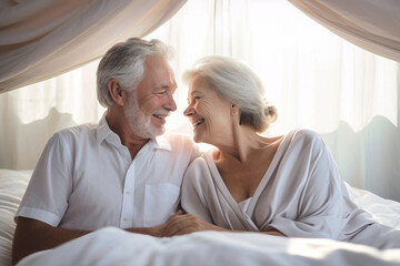 An elderly man and woman sit closely together on a bed, showcasing love and companionship in their golden years