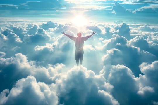 Silhouette of a person with arms spread wide standing above clouds with sunburst in the background, conveying freedom and inspiration.
