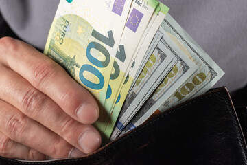 Man handing wallet with 100 euro and 100 dollars banknotes
