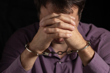 Businessman in handcuffs arrested for financial fraud, sitting in interrogation room