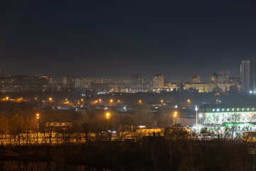 Fototapeta na wymiar Night cityscape of the big city. Bright, multi colored light on empty streets. Apartment buildings in bedroom town area. Kyiv in end of march 2024. Ukraine.