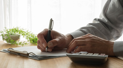 Hand of a man writing on paper at the work table. Businessman working