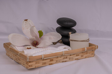 Smooth round hot stone massage stones on grey background. Candle and magnolia flower. Spa therapy....