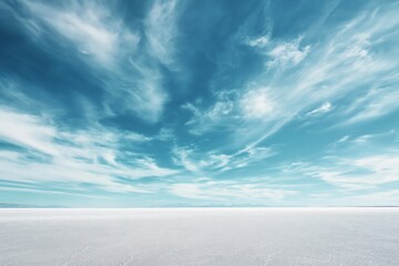 A vast white salt flat under a vibrant blue sky with dynamic wispy clouds, conveying a sense of open space and tranquility.