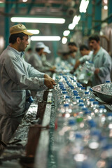 workers in water bottling plant, several men working in factory