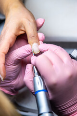 Manicurist using electric file for nail care in salon