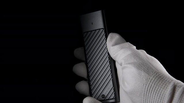 In the Darkness: Hand Securely Grasping High-Speed M.2 SSD Case. High quality photo