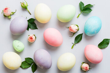 Happy Easter. Easter eggs on colored table with yellow roses. Natural dyed colorful eggs background top view with copy space