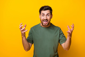 Photo of angry furious guy dressed green t-shirt rising arms hands screaming isolated yellow color...