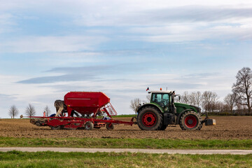 Fototapeta premium Farmer in tractor preparing farmland