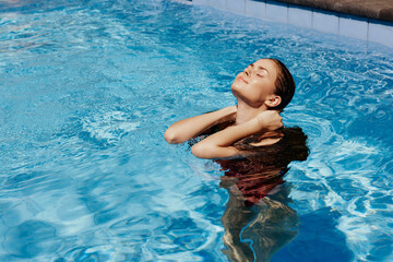 Happy woman swimming in pool in red swimsuit with loose long hair in sunshine, skin protection with...