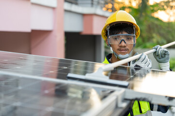 Asian male worker uses a rubber sheet and water to clean the solar panels on the roof of house....