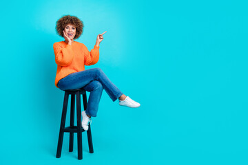 Full length photo of astonished positive person sit chair direct finger empty space isolated on...