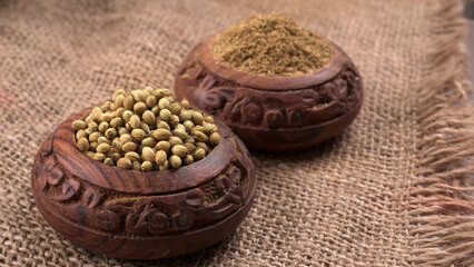 Dried coriander seeds with fresh green leaf isolated on wooden background. Top view. Flat lay
