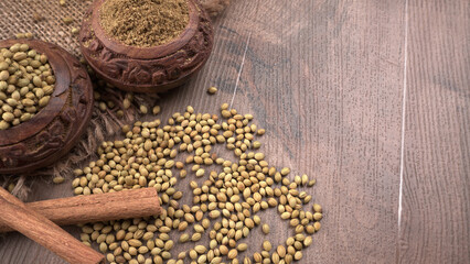 Dried coriander seeds with fresh green leaf isolated on wooden background. Top view. Flat lay