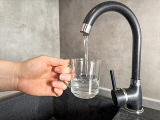 Close up woman filling a glass of water at the kitchen sink