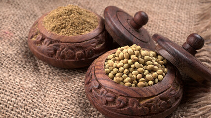 Dried coriander seeds with fresh green leaf isolated on wooden background. Top view. Flat lay