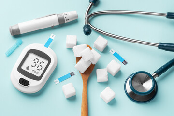Sugar cubes in spoon with blood glucose meter, lancet and stethoscope on blue background - obrazy, fototapety, plakaty