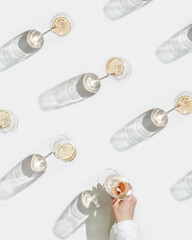 Many glasses of white wine, woman hand take one, creative top view pattern, minimal style flat lay. Wine glass at sunlight, sun shadows and shiny glare glass. Alcohol drinks summer party concept