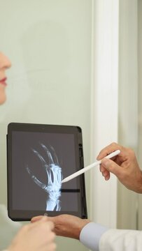 Vertical video of a Medical professionals assess an x-ray on a tablet in a clinical environment