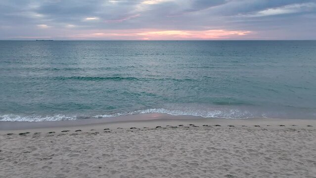 Tropical beach on sunrise, foamy ocean waves washing sand. Waves hitting sand beach on sunrise