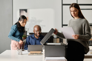 Young Woman Checking Printed Document In Office