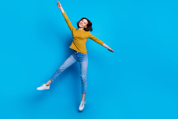 Obraz premium Full length photo of cheerful cute lady dressed shirt jumping high rising hands arms empty space isolated blue color background