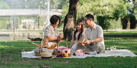 Family day, family picnic together at the park. Retired grandparent take granddaughter to relax and spend time together at the park