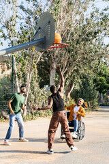 Latin man on wheelchair playing baskteball with African American and hispanic friends
