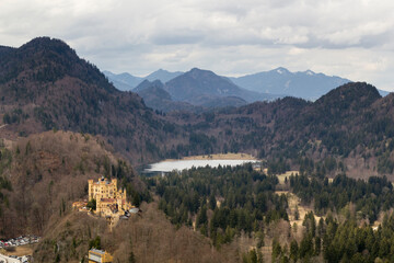 Blick von oben auf Schloss Hohenschangau, den Schwansee und das Bergpanorama bei Füssen im...