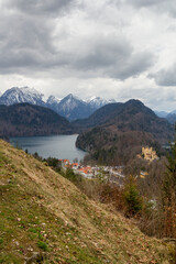 Blick von oben auf Schloss Hohenschangau, den Schwansee und das Bergpanorama bei Füssen im...