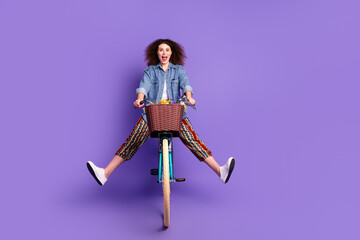 Obraz premium Full size portrait of pretty young woman ride bike empty space ad wear denim shirt isolated on purple color background
