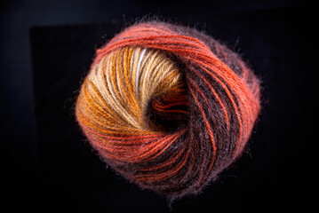 A ball of yarn with a brown and orange color. The yarn is twisted and has a spiral shape