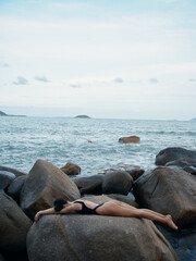 Fototapeta premium Summer Sensuality: A Beautiful Woman in a Sexy Swimwear Poses on the Beach