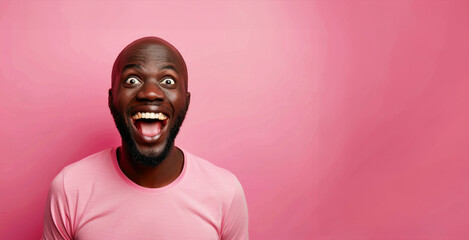 A man with a big smile on his face is wearing a pink shirt. He is looking at the camera and he is happy. Bald black guy smiling with mouth closed, eyes wide and excited of winning a prize
