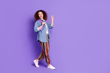 Full body portrait of pretty young woman show v-sign walk empty space wear denim shirt isolated on purple color background