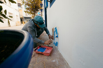 Caucasian adult man painting decorative cats on a tourist house building