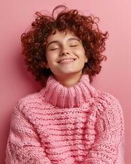 A woman with curly hair wearing a pink sweater