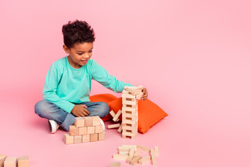 Full body photo of cute little boy play jenga wooden blocks game wear trendy aquamarine clothes...