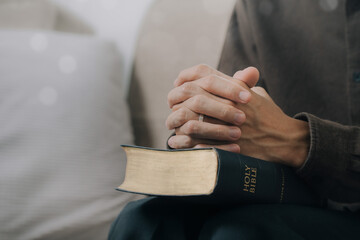 Christian man hands folded on the Holy Bible to pray and worship God in the sunday morning.spirituality, religion,believe.Christian life.Studying the word of God in church.