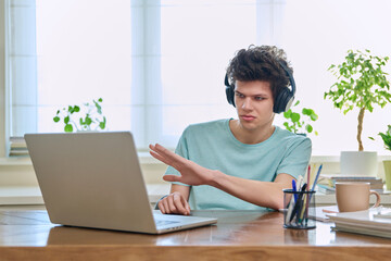 Guy student in headphones looking at web cam computer, talking studying online