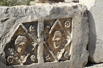 Historical stone bas-relief with carved faces in ancient city of Myra on sunny day. Dead...