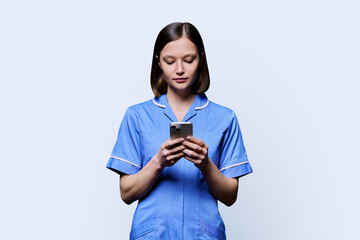 Young female nurse using smartphone, on white background