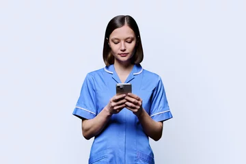 Tuinposter Young female nurse using smartphone, on white background © Valerii Honcharuk