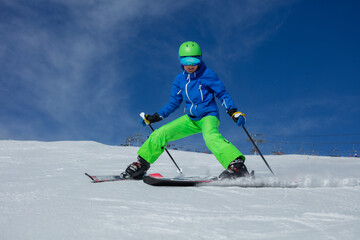 Teenage person ski on a snowy slope with blue sky in backdrop