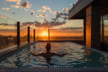 Zelfklevend Fotobehang individual relaxing in penthouse rooftop pool with a sunset view © studioworkstock