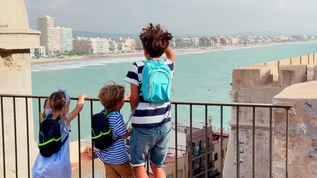 Children gaze at ocean from historic site, point with fingers